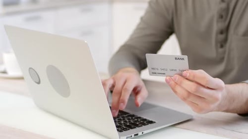 Person Using Laptop and Holding Credit Card
