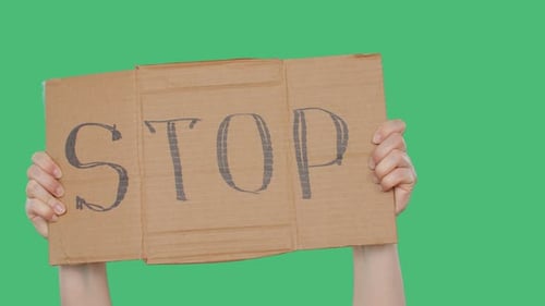 Protester Holding Stop Cardboard Sign in Hands on Green Background