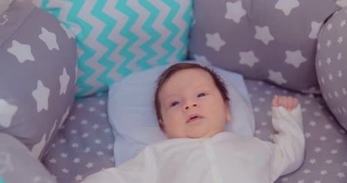 Милый малыш лежит в красивой уютной кроватке, оглядывается по сторонам