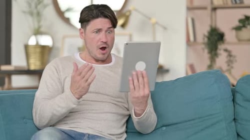 Man Using Tablet and Looking Surprised on Couch