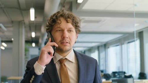Businessman Speaking on Phone while Walking in Office