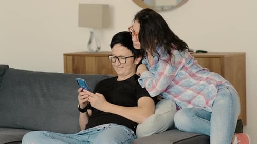 Couple Relaxing at Home, Using a Smartphone Together