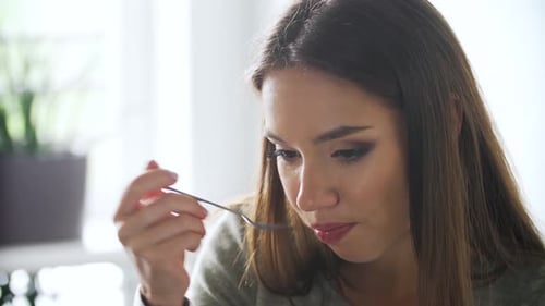 Woman Eating with Spoon Smiling at Camera