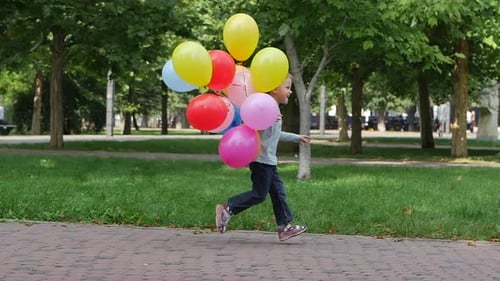 Happy Child Running with Balloons in Sunny Park