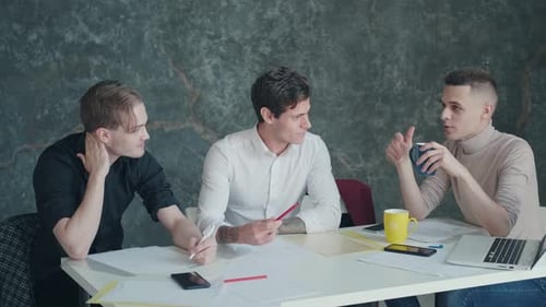 Colleagues Have Fun Talking During a Break in the Office. Three Young Men Drink Coffee and Chating