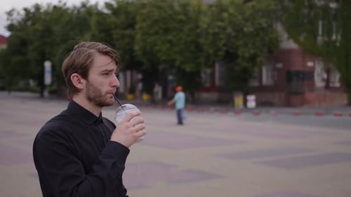Young Adult Sipping Drink in Urban Setting