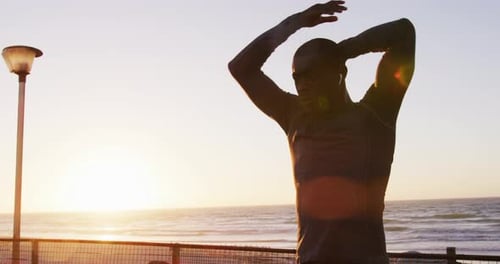 Athletic Man Stretching on Beach at Sunrise