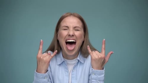 Yeah, awesome. Portrait of excited rocker woman showing rock and roll hand gesture
