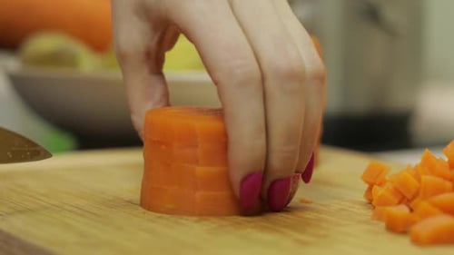 Female Housewife Hands Slicing Carrots Into Pieces in the Kitchen