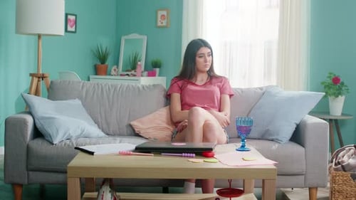 Young Woman Sitting on Sofa, Looking Sad