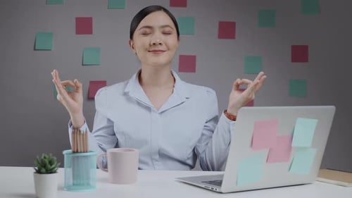 Young Adult Meditating at Desk in the Office