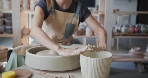 Une potière travaille avec de l'argile sur la roue à poterie.