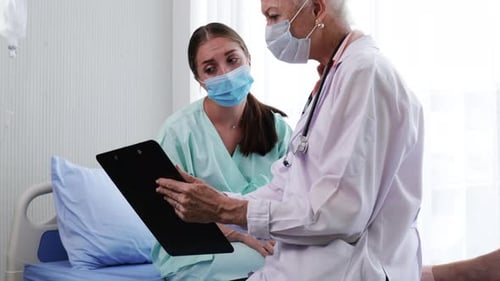 Mature Doctor Discussing Chart with Young Adult Patient