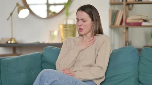 Young Woman Coughing While Sitting on Couch