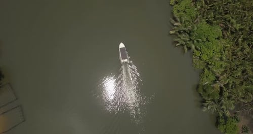 Aerial Top View of Little White Boat Traveling Slow Along Beautiful Calm Jungle River with Sun