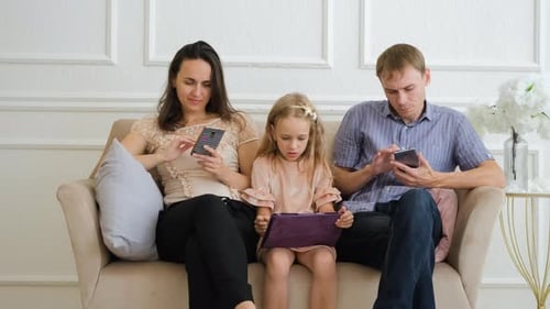 Family Together on Couch Using Mobile Devices