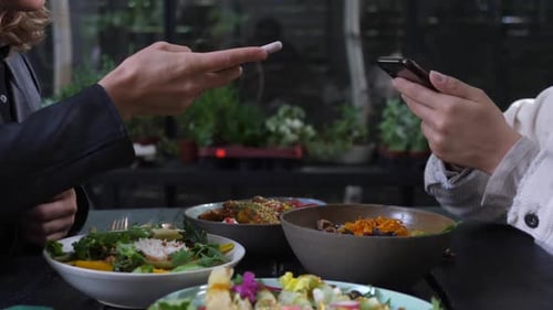 People Using Smartphones During Meal at Restaurant