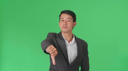 Happy Asian Business Man Showing Thumbs Up And Thumb Down Gesture In The Green Screen Studio