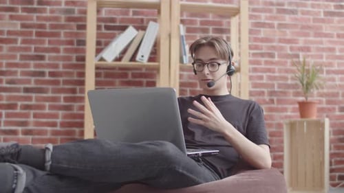 The Guy Communicates Via Video Chat Gesticulating in Front of a Web Camera, A Freelancer Works