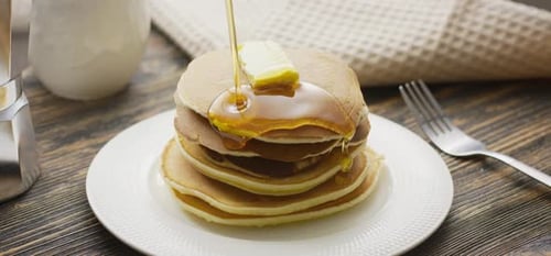 Food and Cooking Concept. Stack of Pancakes with Butter and Warm Maple Syrup in Slow Motion