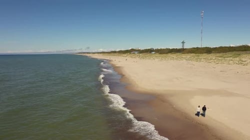Dos mujeres caminan por la playa, vista desde un Zumbido