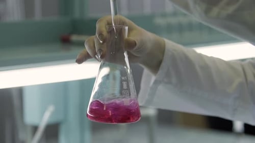 Scientist Titrating Colorful Liquid in Erlenmeyer Flask