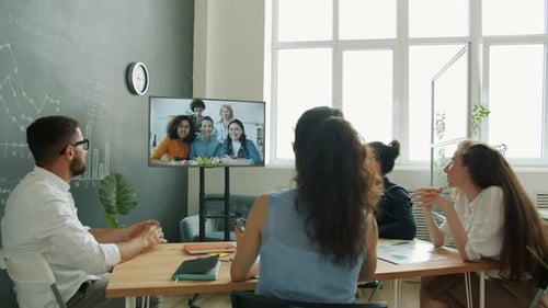 Vielfältige Gruppe von Geschäftsleuten, die per Videoanruf mit Kolleginnen chatten und auf das Display schauen