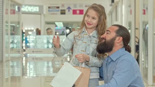 Little Girl Pointing Away, Showing Something To Her Father at the Shopping Mall