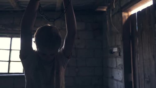 Un adolescent kidnappé est assis enchaîné dans une chambre sombre et attend la libération