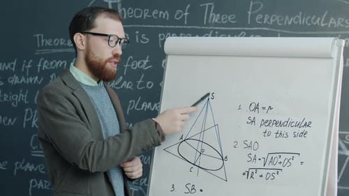 Portrait of College Maths Teacher Pointing at Drawings on Flipchart Speaking and Looking at Camera