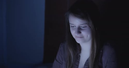 Young Adult Woman in Dark Room with Screen