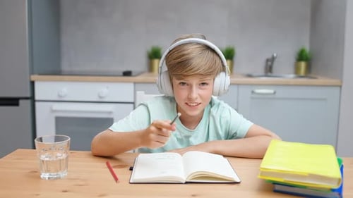Child Studying at Table with Headphones On