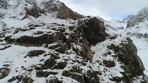 Lone Hiker Climbing Snowy Mountain Ridge in Winter