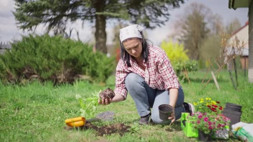 The Girl Plants Flowers in the Garden