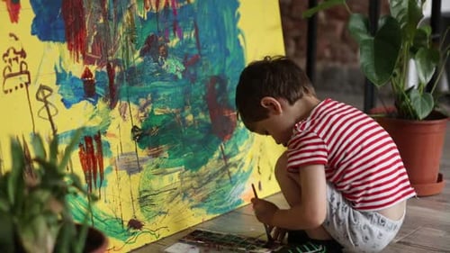 Child Engaged in Painting a Large Colorful Canvas