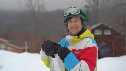 Closeup Shot of a Young Man Wearing a Helmet with a Snowboard in a Mountain Resort. Winter Holidays