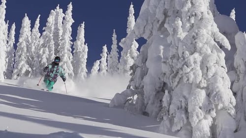A man skiing down a snow-covered mountain in the winter