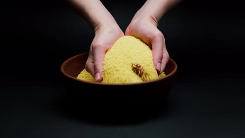 Polenta aus der Schüssel in die Hand nehmen und auf schwarzem Hintergrund gießen