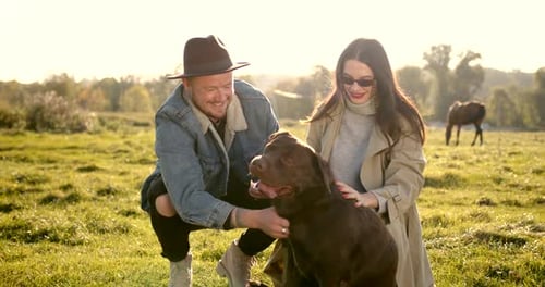 Stylish Modern Couple with a Dog on Meadow