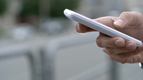 Man Using White Smartphone Outdoors in City
