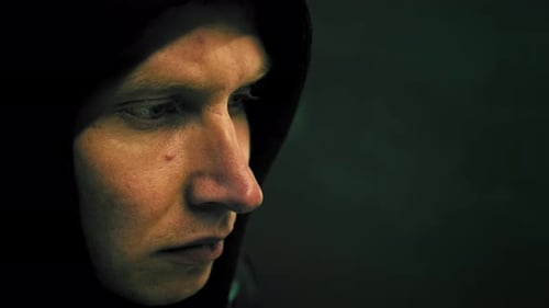 Männlicher Hacker, der an einem Computer für Cyber-Angriff arbeitet, greift sein Gesicht in einem dunklen Büroraum an