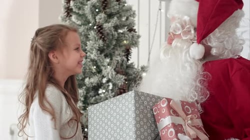 Happy Girl Receiving Gift from Santa Claus at Christmas