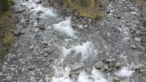 Aerial view of clean fresh mountain river surrounded by autumn green and yellow trees