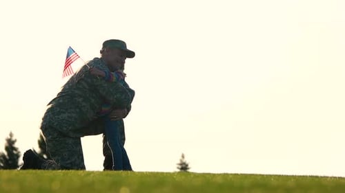 Soldier Kneels to Hug Child on Grassy Field