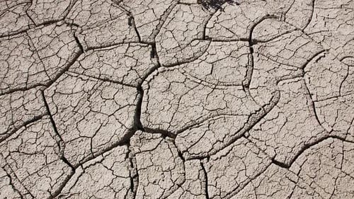 Dry soil with cracks through the mud in the desert