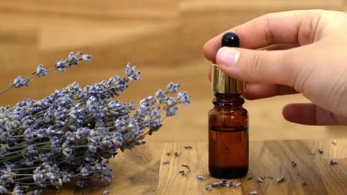 Lavender Oil. A woman picks up a jar of lavender essential oil.