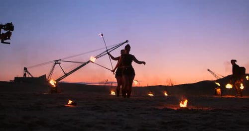 Professionelle Künstler zeigen eine Feuershow bei einem Sommerfestival im Sand in Zeitlupe