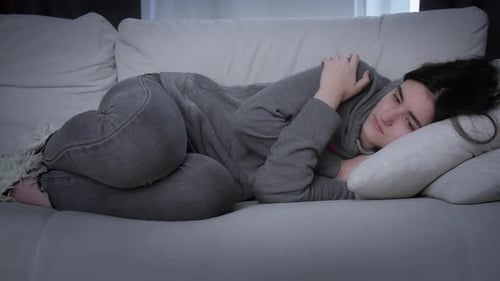 Sad Girl Lying on the Couch Hugging Herself with Arms Motionless Look Concept Life Situation