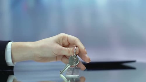 Hand Puts Keys With Insurance Keychain on Table