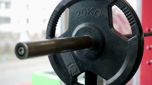 Mann entfernt Teller von der Langhantel nach aktivem Gewichtheben im Fitnessstudio